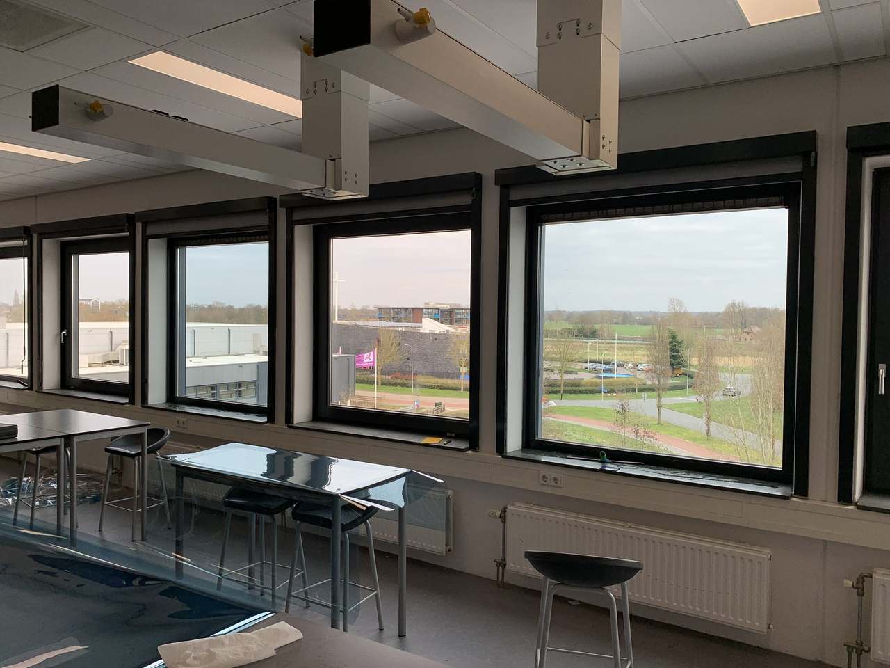 Klaslokaal met een rij ramen, waarvan een deel een lichtblauwe tint heeft door GlassShield